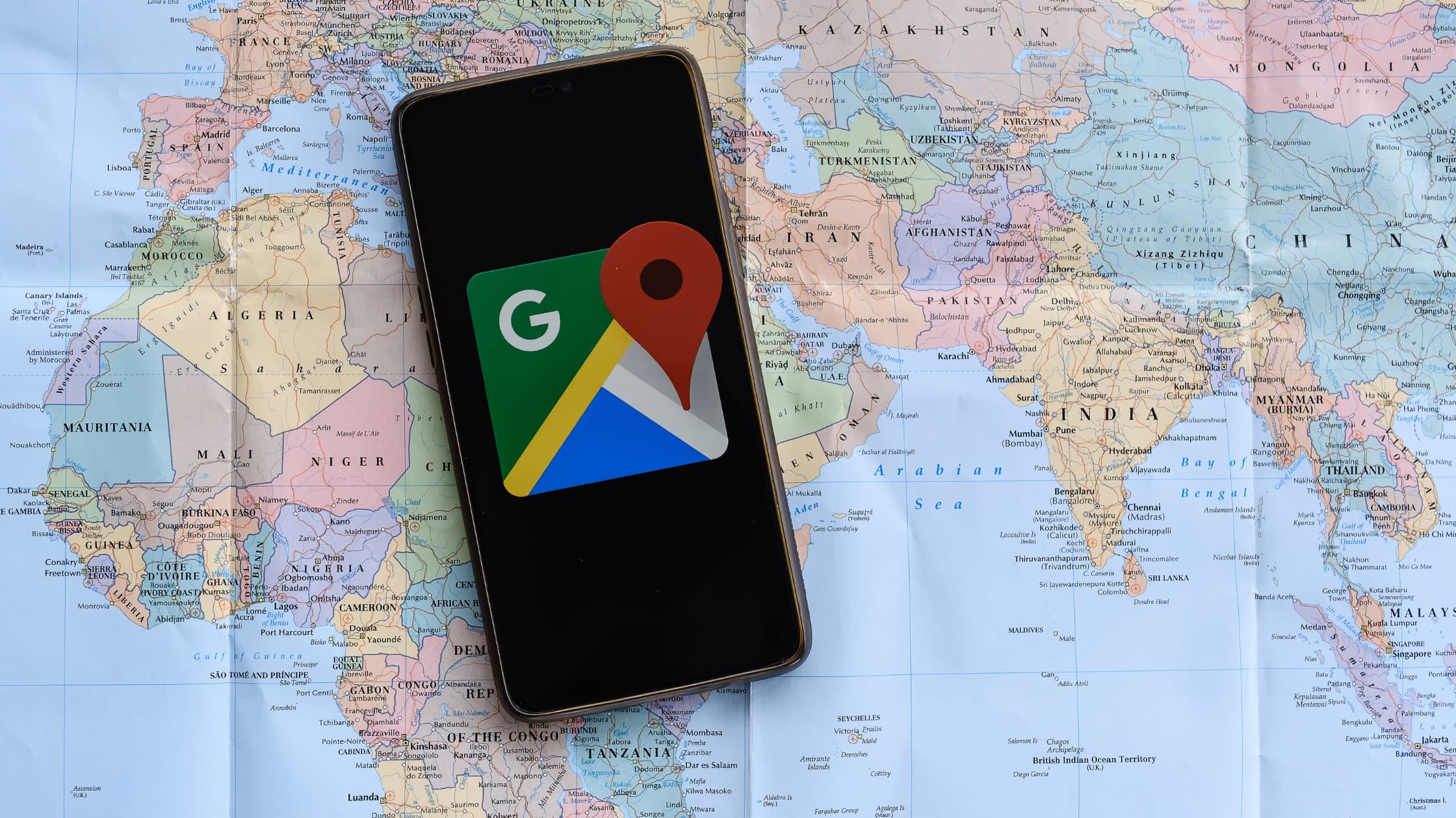 A phone placed on top of a map with Google map app on display
